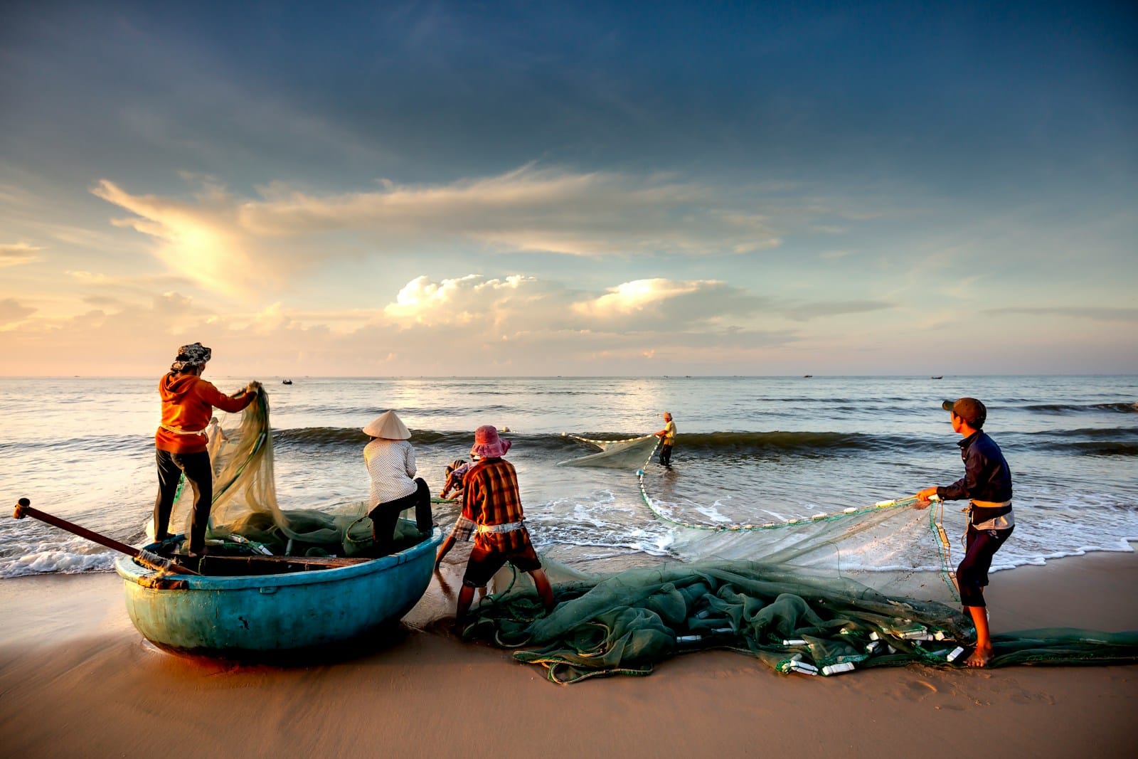 a group of people standing on top of a beach next to a boat