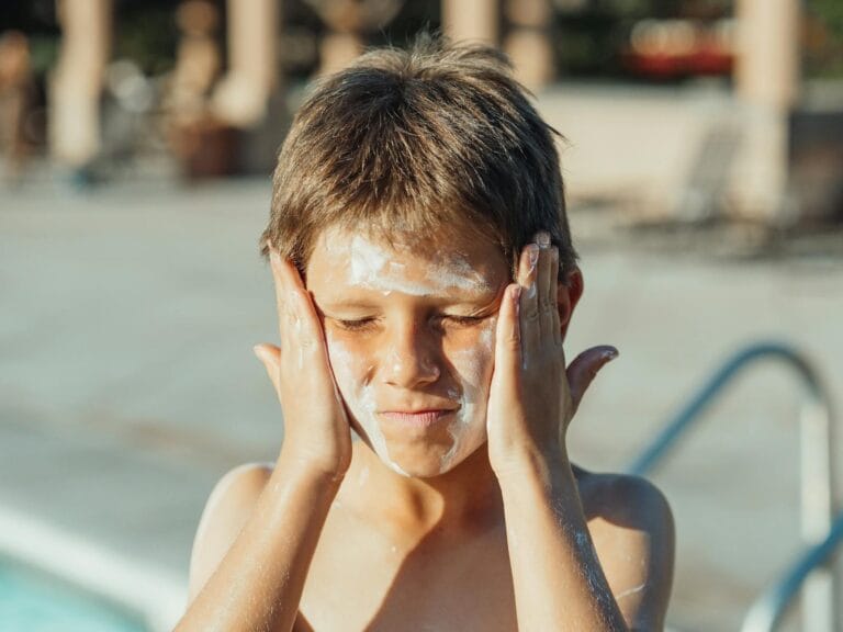 Young boy applying sunscreen cream at a sunny poolside, capturing a summer vacation vibe by pexel