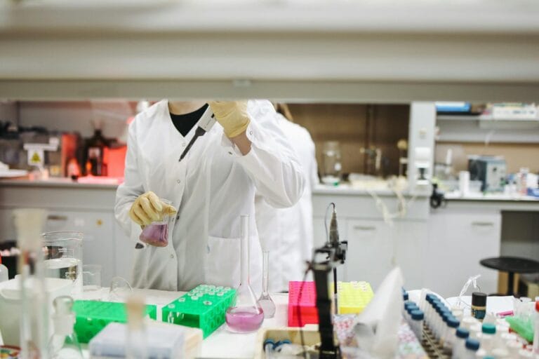 Scientist in a lab coat handling samples for scientific research in a modern laboratory setting. uji sensitivitas antibiotik.