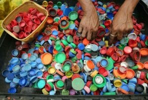 A vibrant assortment of plastic bottle caps being sorted by hand for recycling in Manila. mikroba ekstremofil. Extremophile Microbes