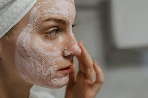 Close-up of a woman applying facial cream as part of her skincare routine, enhancing skin health. data uji