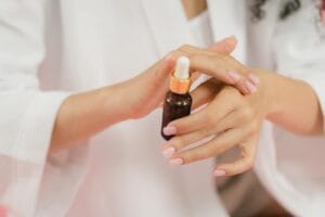 Elegant hands applying skincare serum from a bottle. Manicured nails enhance the beauty of the scene. skincare overclaim.