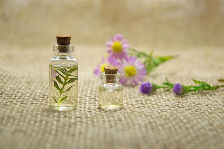 Glass bottles with essential oils and fresh flowers on burlap fabric creating a natural aroma. minyak atsiri.