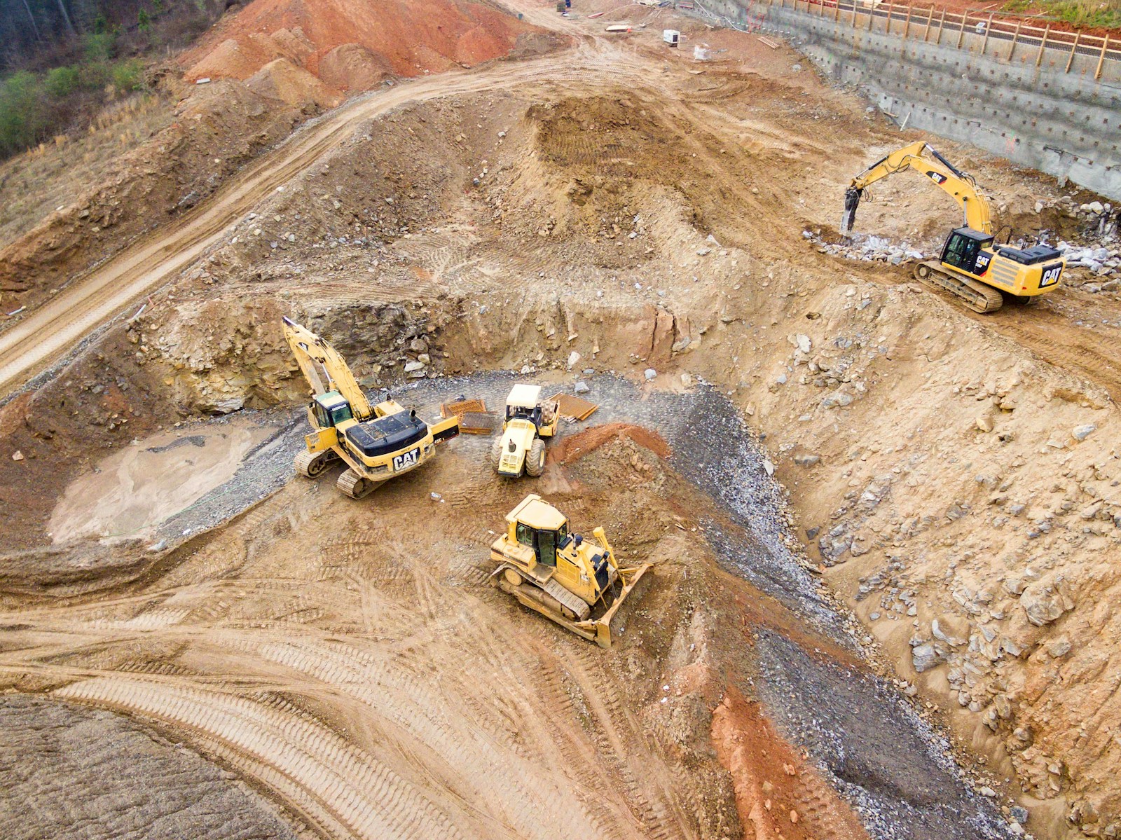top view photography of four heavy equipment on quarry at daytime. air tambang