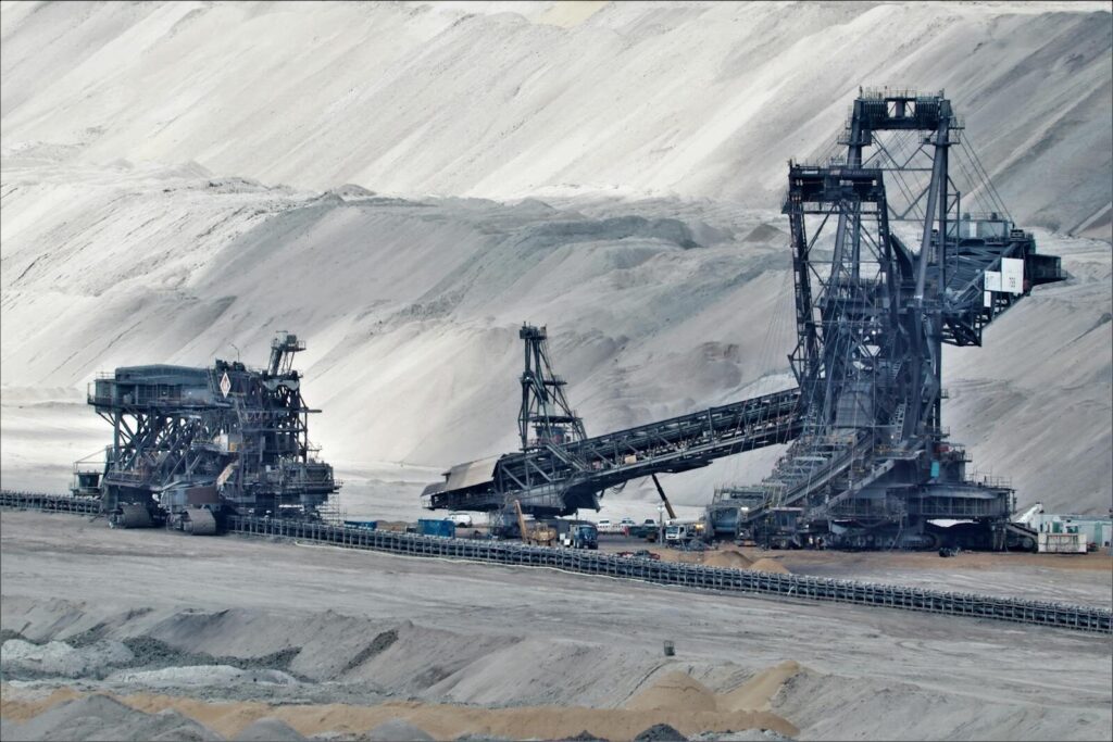 A large bucket wheel excavator operates in a vast industrial mining area, illustrating heavy machinery in action. gold mine.